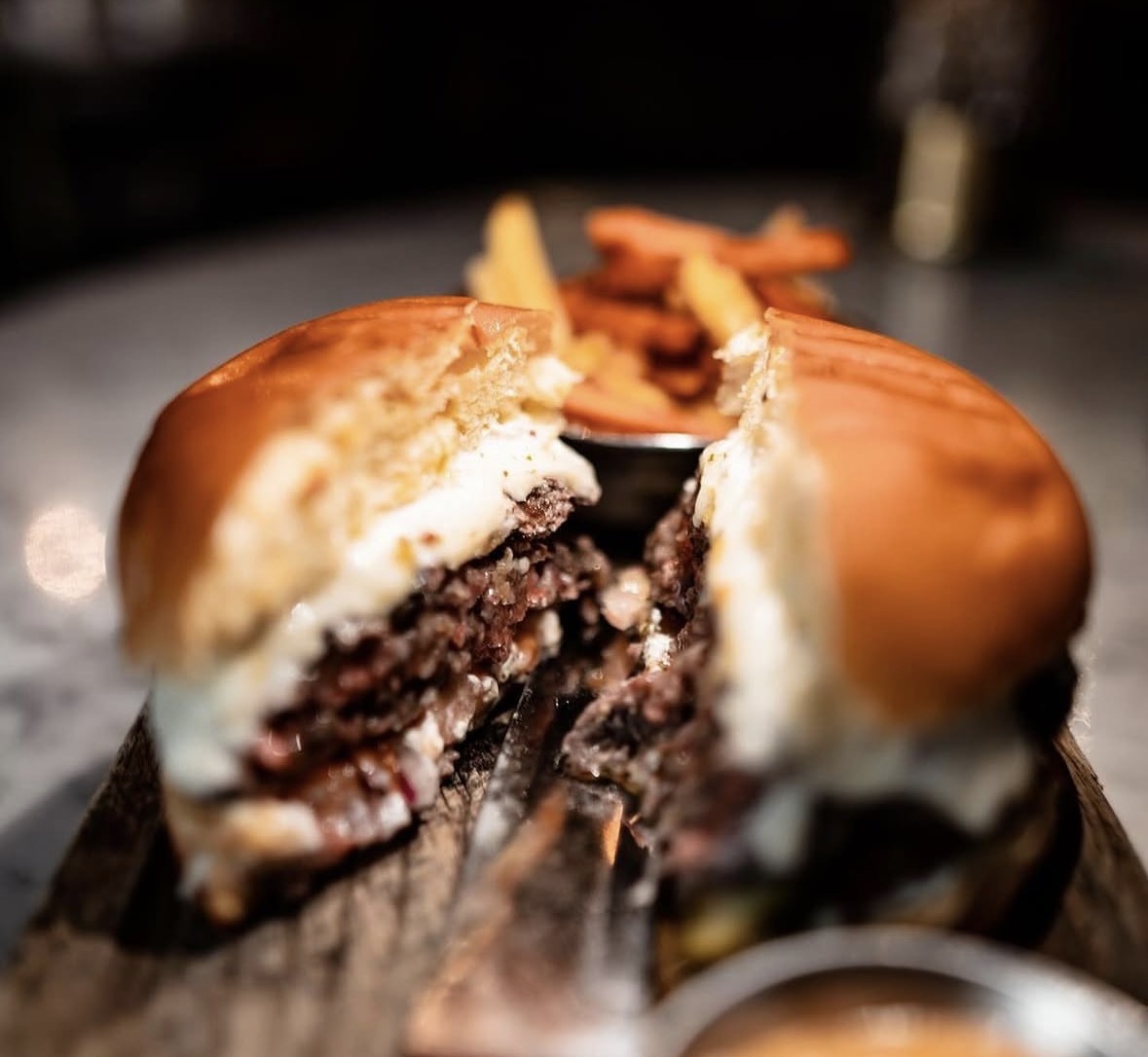 Beef burger split open with melted cheese — served in Alethriko
